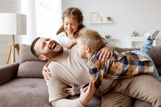 Vater spielt mit zwei Kinder im Wohnzimmer