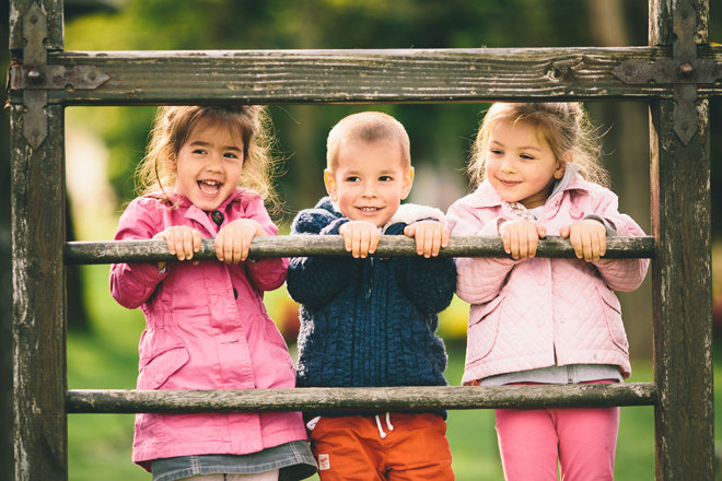 Drei kleine Kinder auf einem Holzzaun