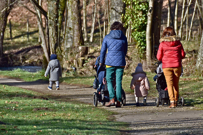 Mütter mit Kleinkindern gehen im Park spazieren