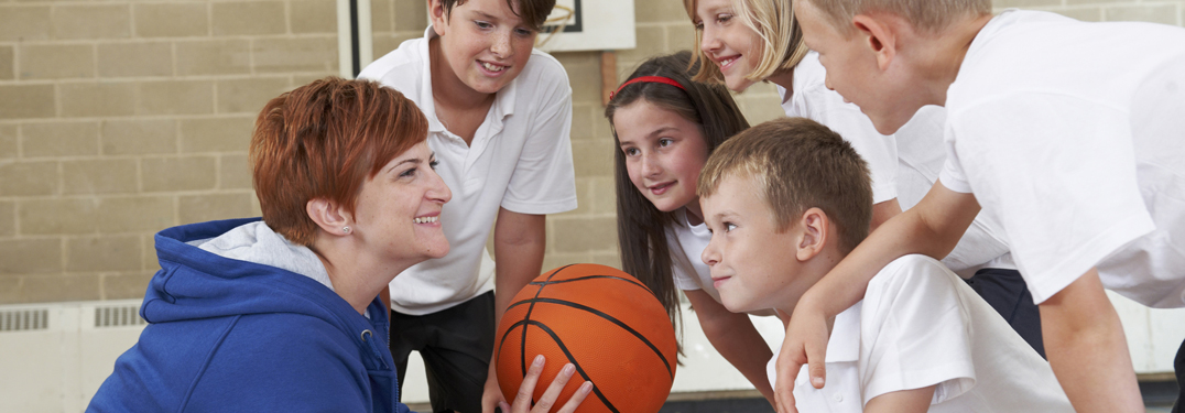 Kinder mit Trainerin beim Basketballspielen